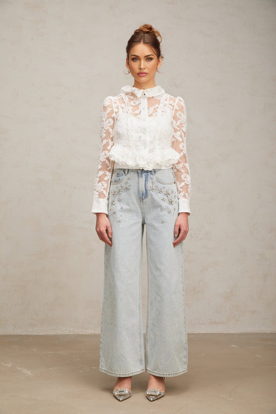 A white blouse with delicate floral embroidery and lace detailing named Karine