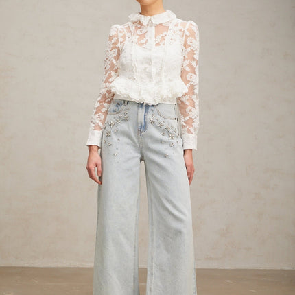 A white blouse with delicate floral embroidery and lace detailing named Karine