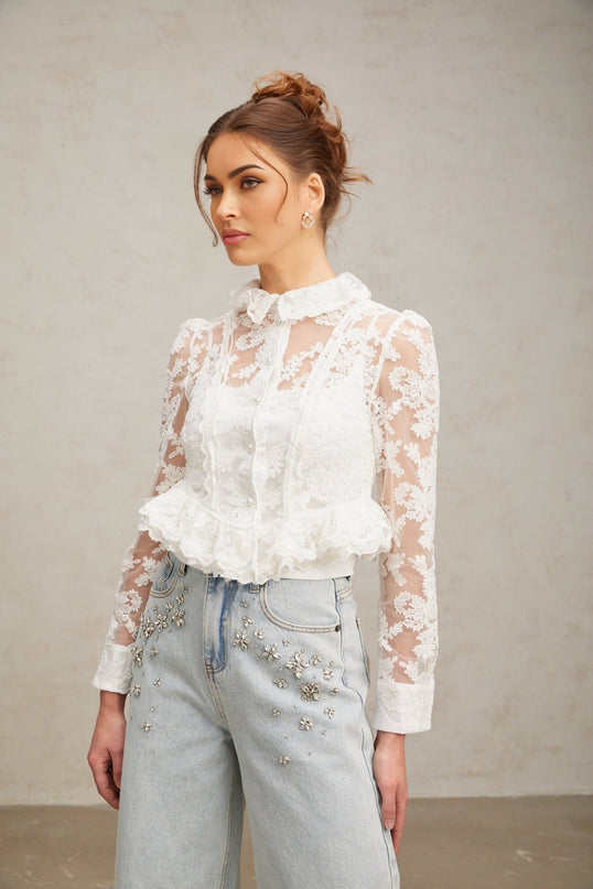 A white blouse with delicate floral embroidery and lace detailing named Karine