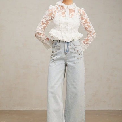A white blouse with delicate floral embroidery and lace details featuring a feminine design and intricate patterns