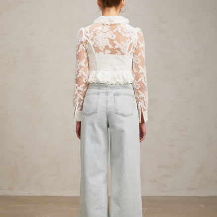 A white blouse with delicate floral embroidery and lace details featuring a feminine design and lightweight fabric