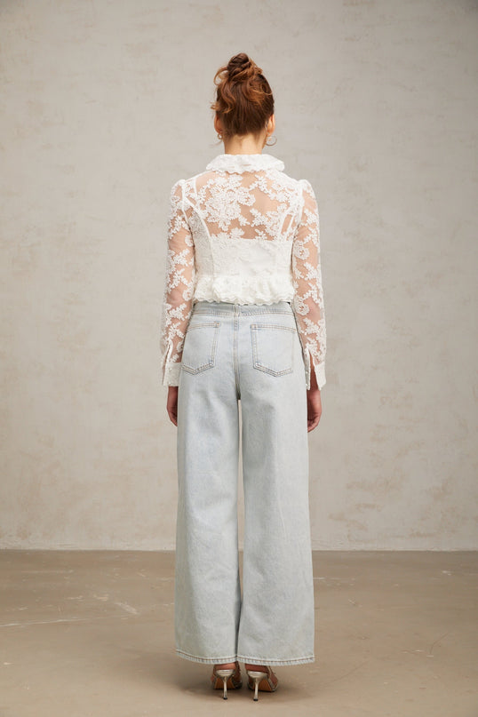 A white blouse with delicate floral embroidery and lace details featuring a feminine design and lightweight fabric