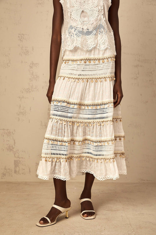 A white bohemian style midi skirt with shirred waistband and flowing fabric falling to mid calf length