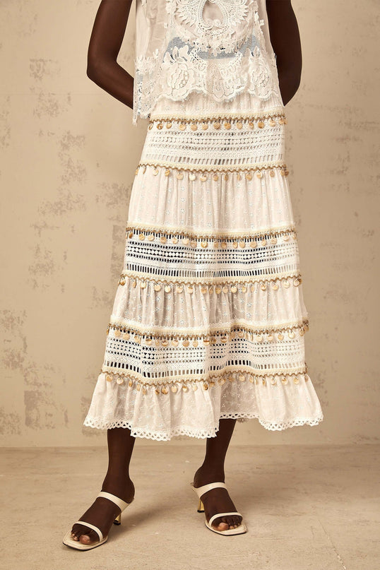 A white bohemian style midi skirt with shirred waistband and flowy fabric falling to mid calf length