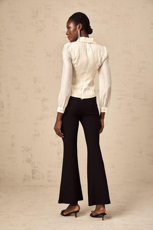 A white buttonup shirt with lace trim and a bow detail at the neckline