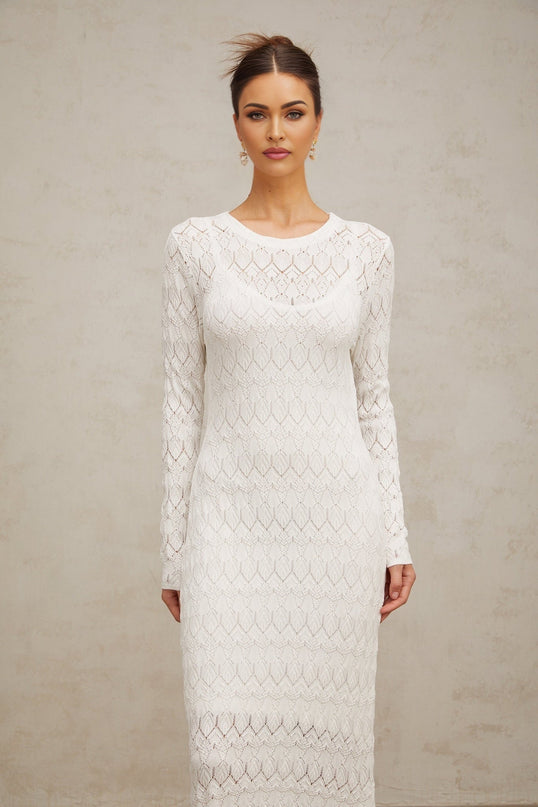 A white crochet knit midi dress with intricate lace patterns hanging on display