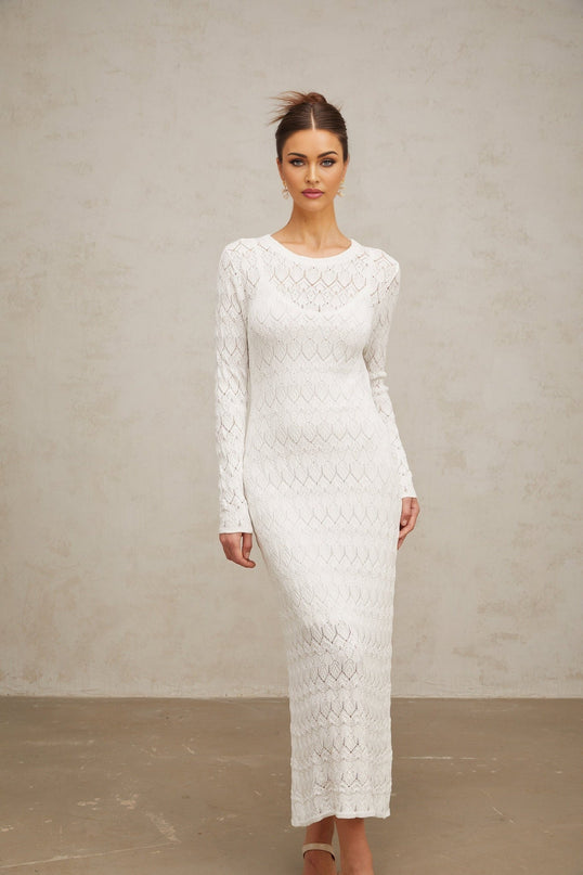 A white crochet knit midi dress with intricate lace patterns hanging on display