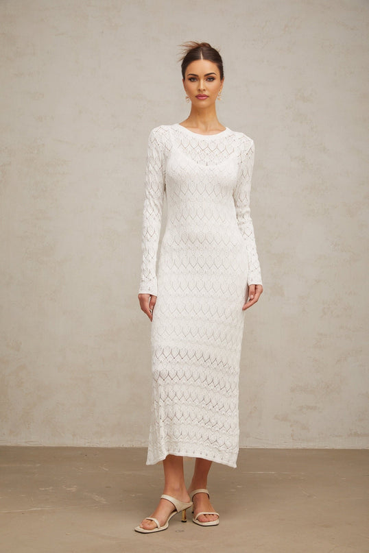 A white crochet knit midi dress with intricate patterns hanging on display