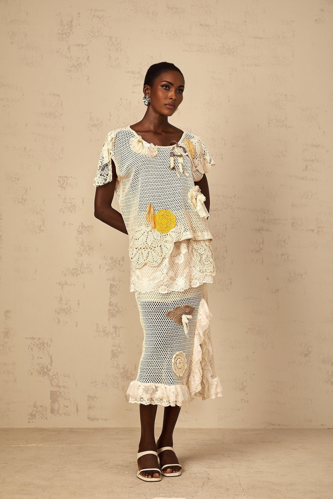 A white crochet knit midi skirt with lace panels featuring an intricate floral pattern and scalloped hem