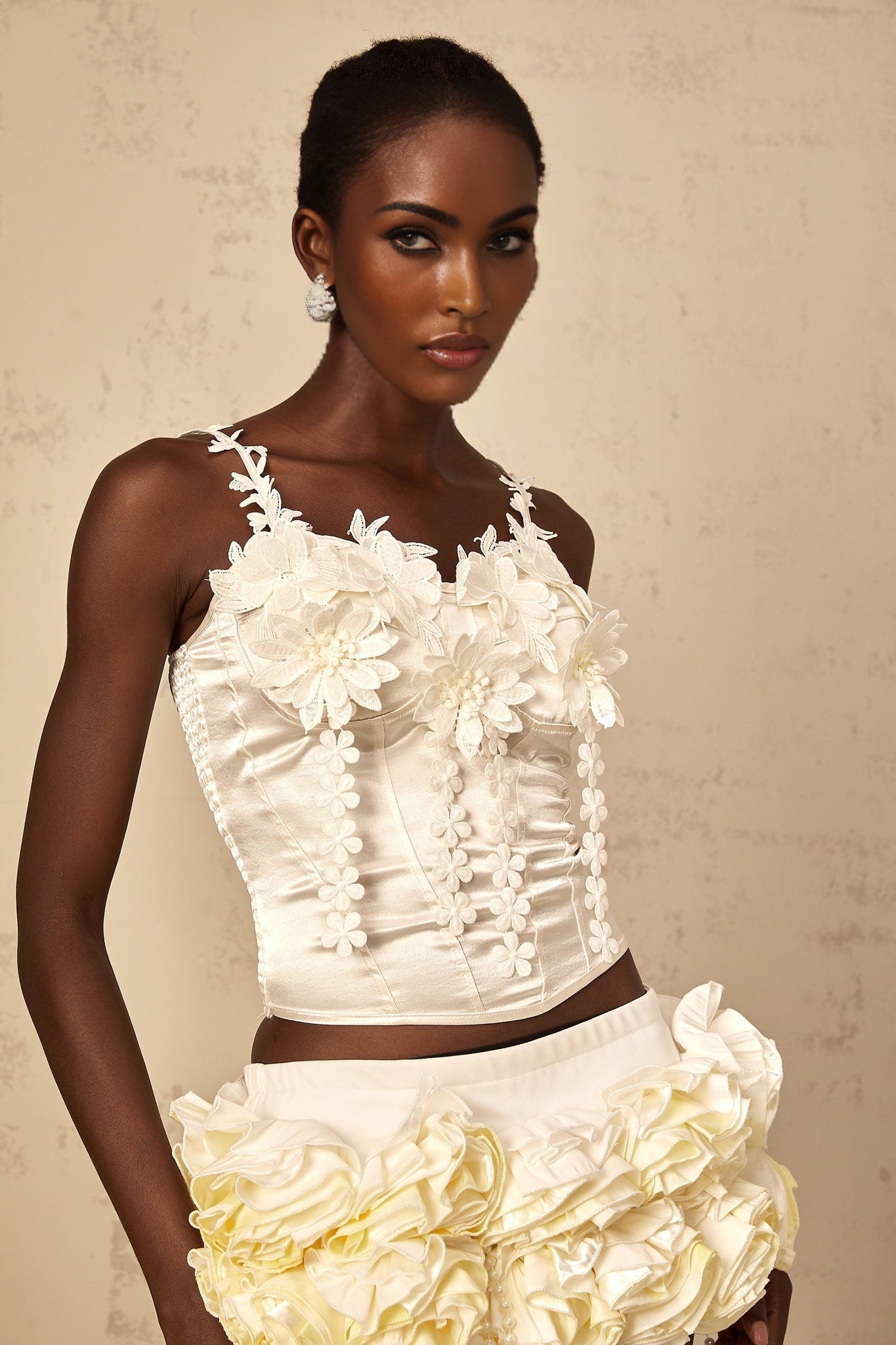 A white cropped top with delicate floral embroidery design featuring short sleeves and a rounded neckline
