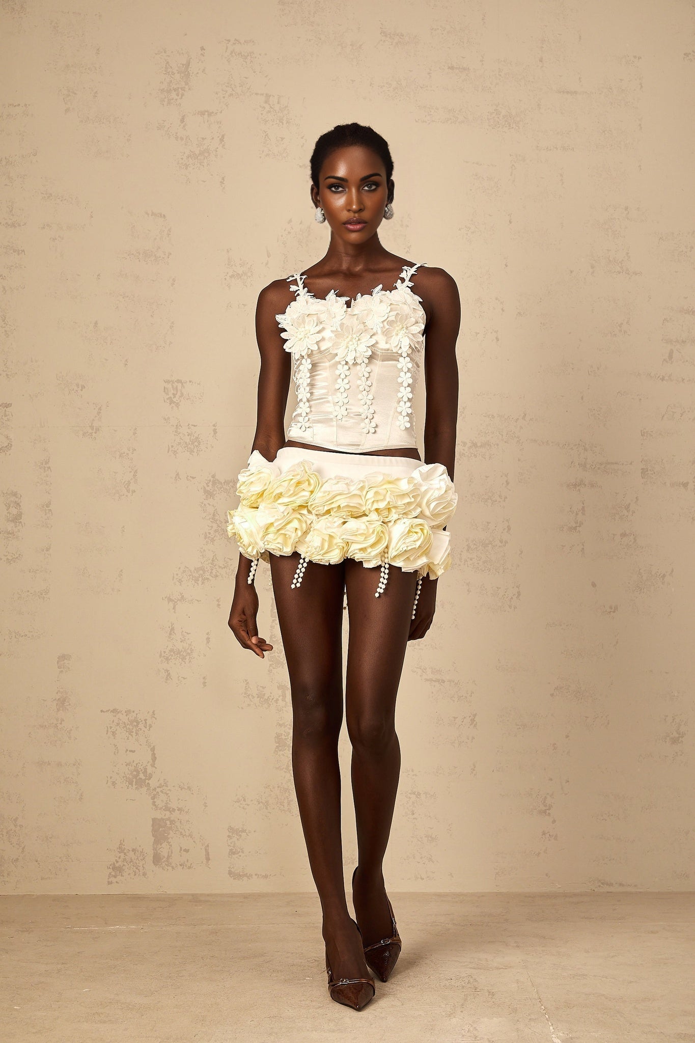 A white cropped top with delicate floral embroidery detail featuring short sleeves and a round neckline