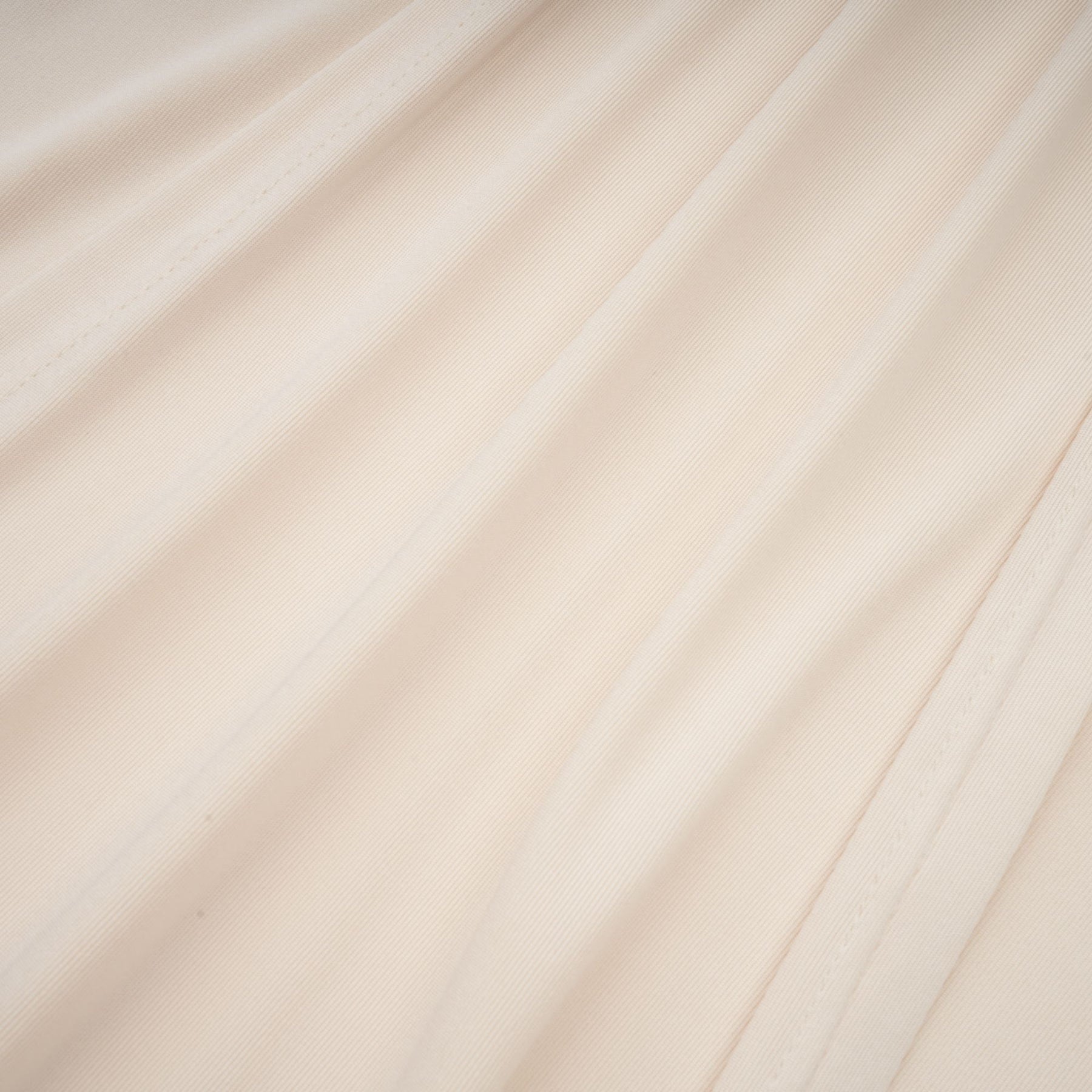 A white floorlength maxi dress with a deep V neckline and draped fabric worn by a model against a plain background