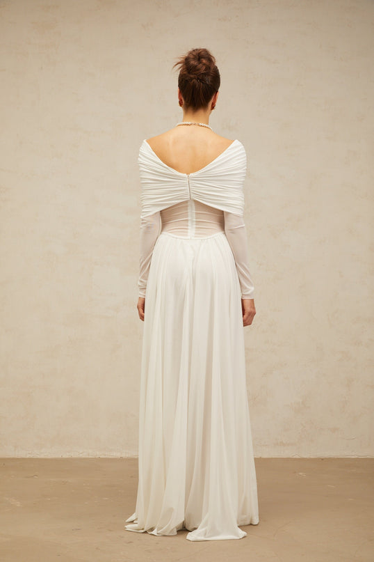 A white floorlength maxi dress with draped detailing and ruching throughout the body creating elegant folds and texture