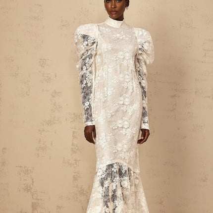 A white floorlength mermaid style dress with floral lace detailing covering the entire garment featuring a fitted bodice and flared skirt