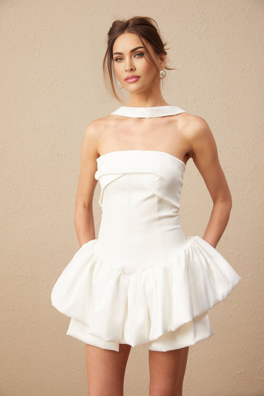 A white halterneck mini dress with ruffled details worn by a model named Olivia featuring a sleeveless design and a short hemline