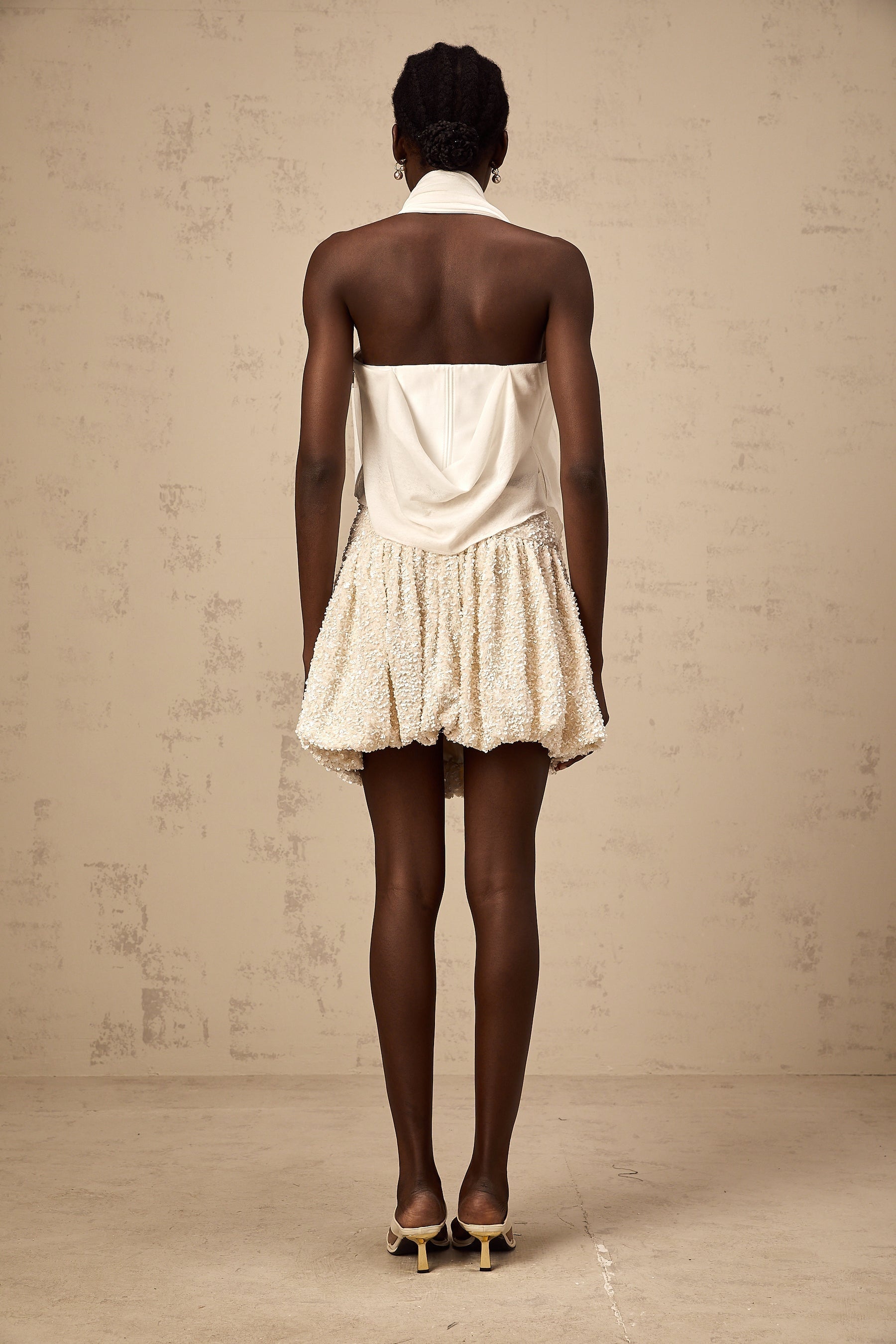 A white halterneck top with floral appliques featuring a sleeveless design and delicate floral embellishments on the fabric