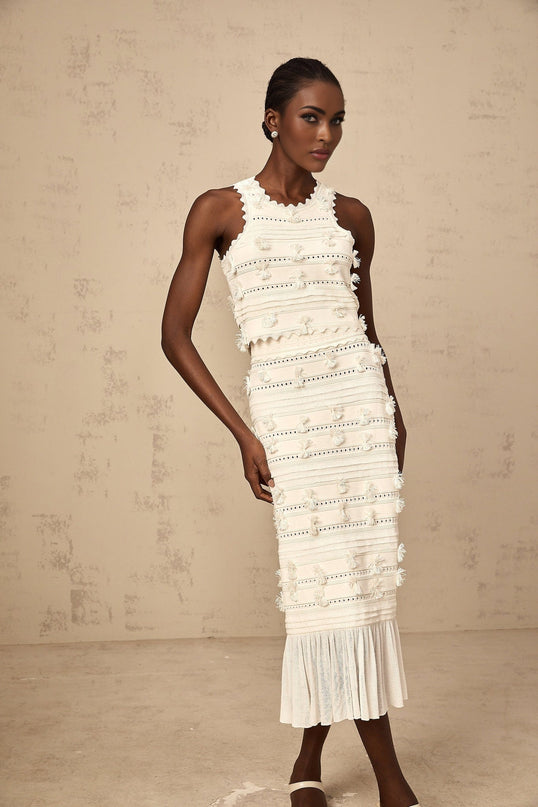 A white knit matching set featuring a top and skirt with pointelle trim details The top has a fitted silhouette while the skirt appears to be slightly flared Both pieces showcase delicate pointelle patterns along the edges creating a feminine and elegant look