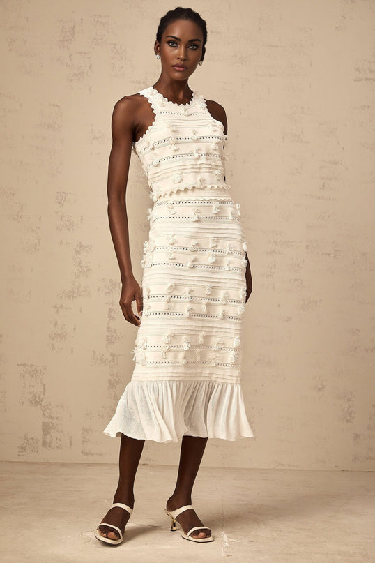 A white knit twopiece outfit consisting of a top and skirt with delicate pointelle trim details The set features a matching design in a light and airy fabric