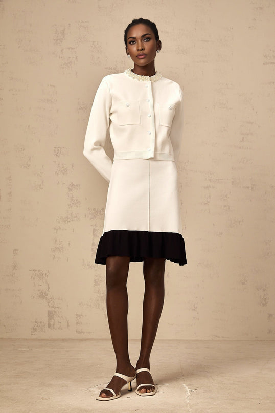 A white knitted cardigan adorned with faux pearl embellishments featuring a classic design and button front closure