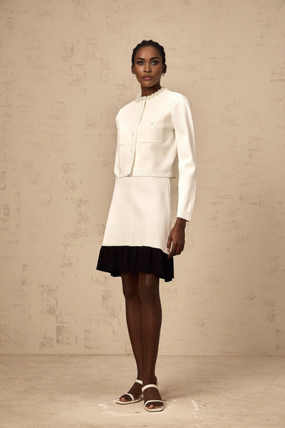 A white knitted cardigan adorned with faux pearl embellishments featuring a classic design with button closure