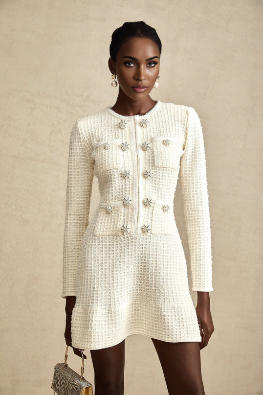 A white knitted mini dress with a flared skirt and short sleeves on a female model against a plain background
