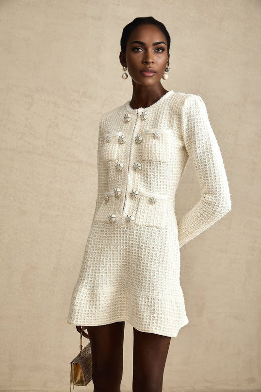 A white knitted mini dress with a flared skirt and short sleeves on a model against a plain background