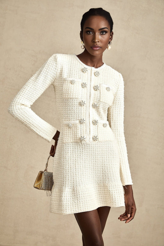 A white knitted mini dress with a flared skirt design named Liane worn by a model against a plain background