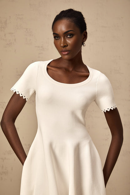 A white knitted mini dress with cutout details and a fleur design featuring a short hemline and fitted silhouette