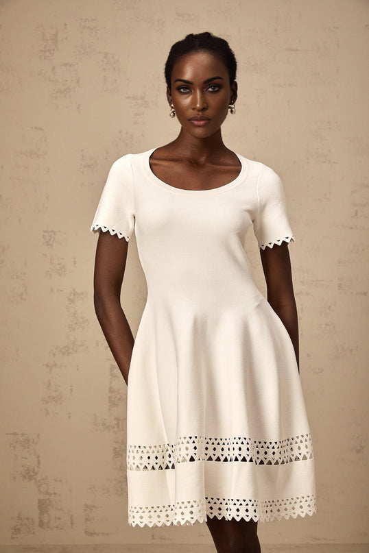 A white knitted mini dress with cutout details featuring a fitted silhouette and short length
