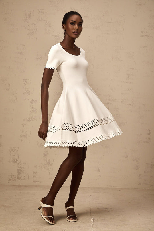 A white knitted mini dress with cutout details featuring a fitted silhouette and short length