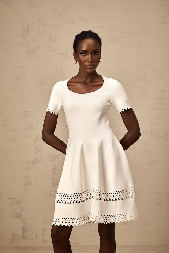A white knitted mini dress with cutout details featuring a fitted silhouette and short length
