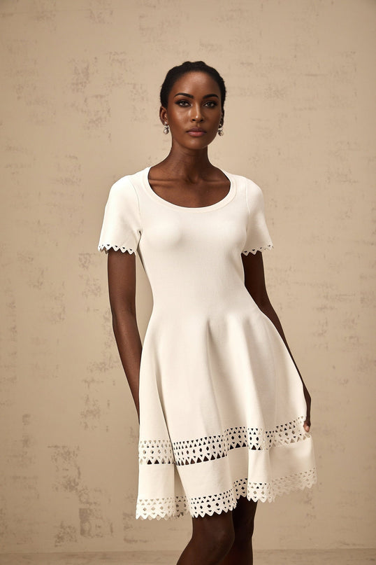 A white knitted mini dress with cutout details featuring a fleur design pattern