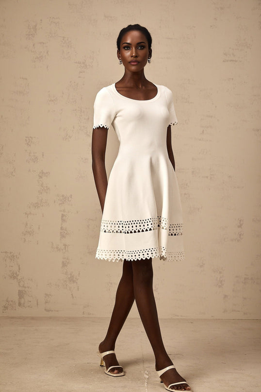 A white knitted mini dress with cutout details featuring a floral pattern and a short hemline