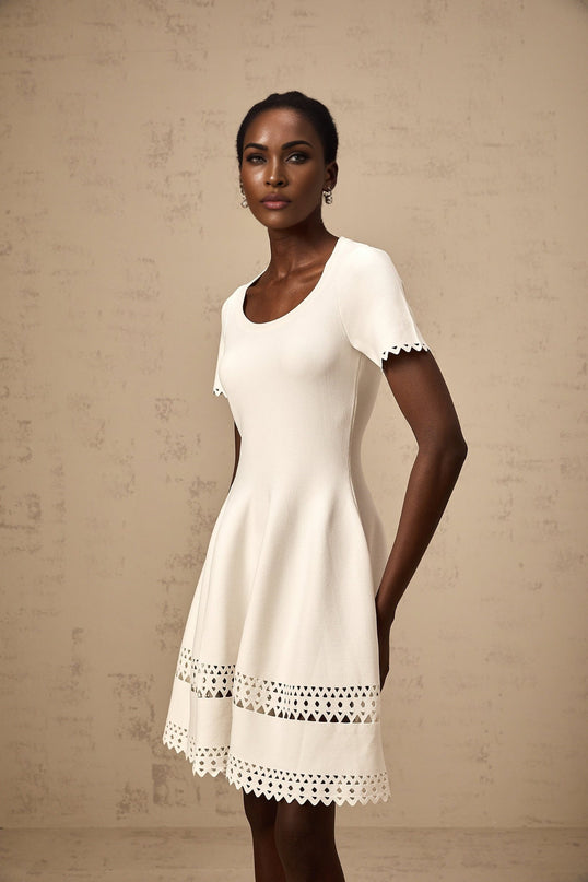 A white knitted mini dress with cutout details featuring a floral pattern and a short hemline