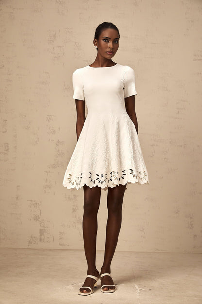 A white knitted mini dress with jacquard pattern and cut out details worn by a model named Emilie