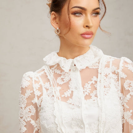 A white lace blouse with floral embroidery patterns featuring a delicate feminine design named Karine