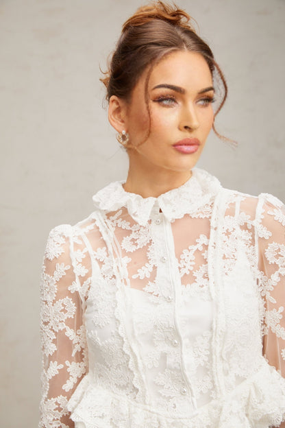 A white lace blouse with floral embroidery patterns featuring a delicate feminine design named Karine