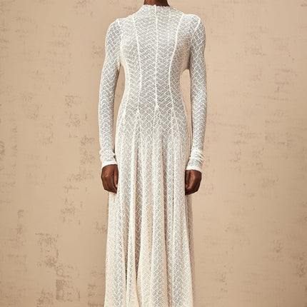 A white lace maxi dress with a wavy pattern design featuring long sleeves and a flowing skirt