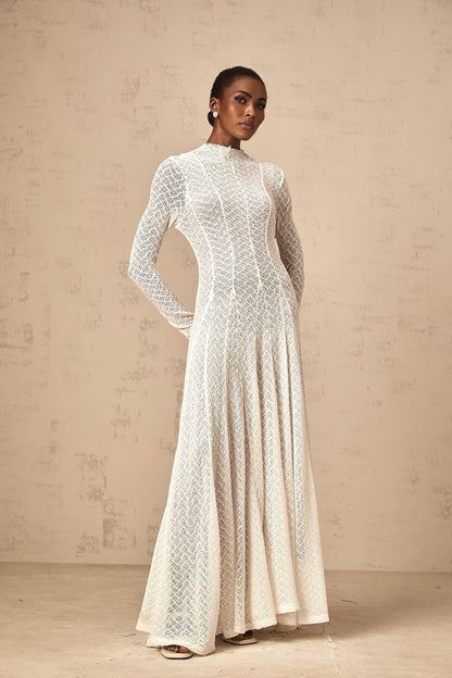 A white lace maxi dress with a wavy pattern featuring a long flowing skirt and delicate lace details throughout