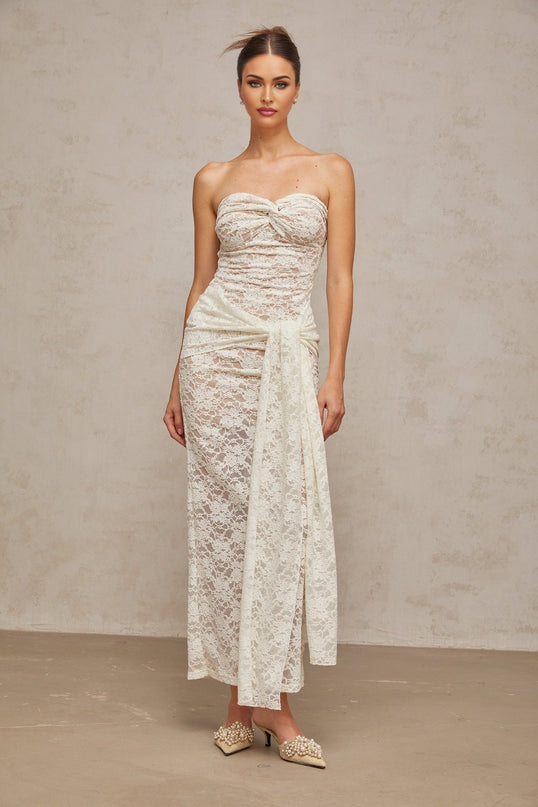 A white lace midi dress with draped details named Wilhelmine on a plain background