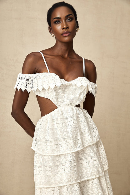 A white lace midi dress with openwork design and delicate floral patterns worn by a model standing against a plain background