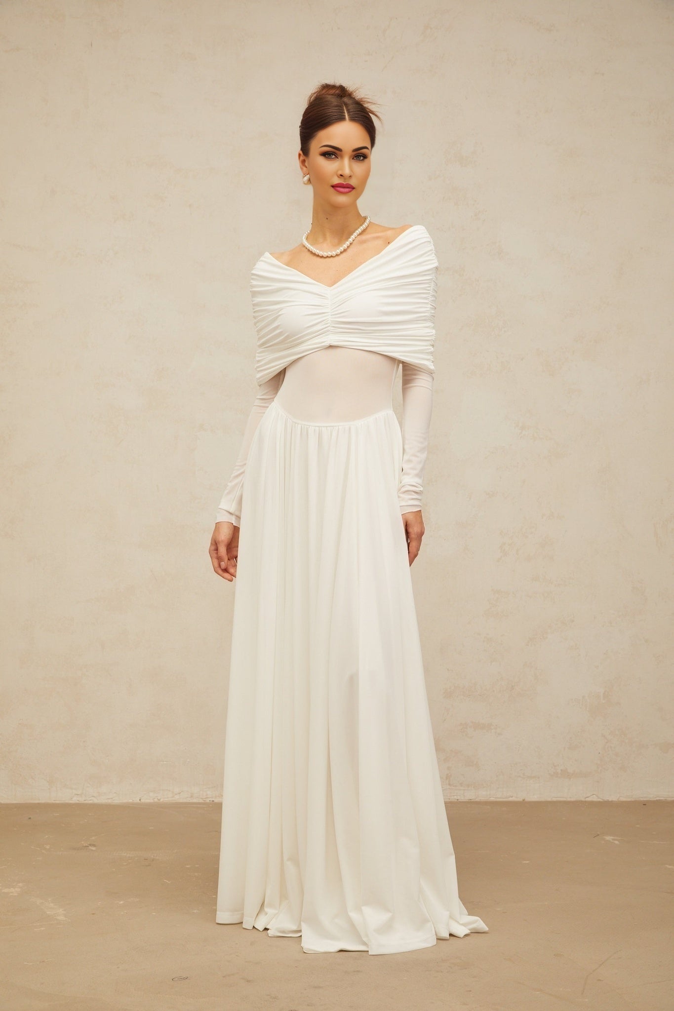 A white long maxi dress with ruched detailing and draped elements on a female model