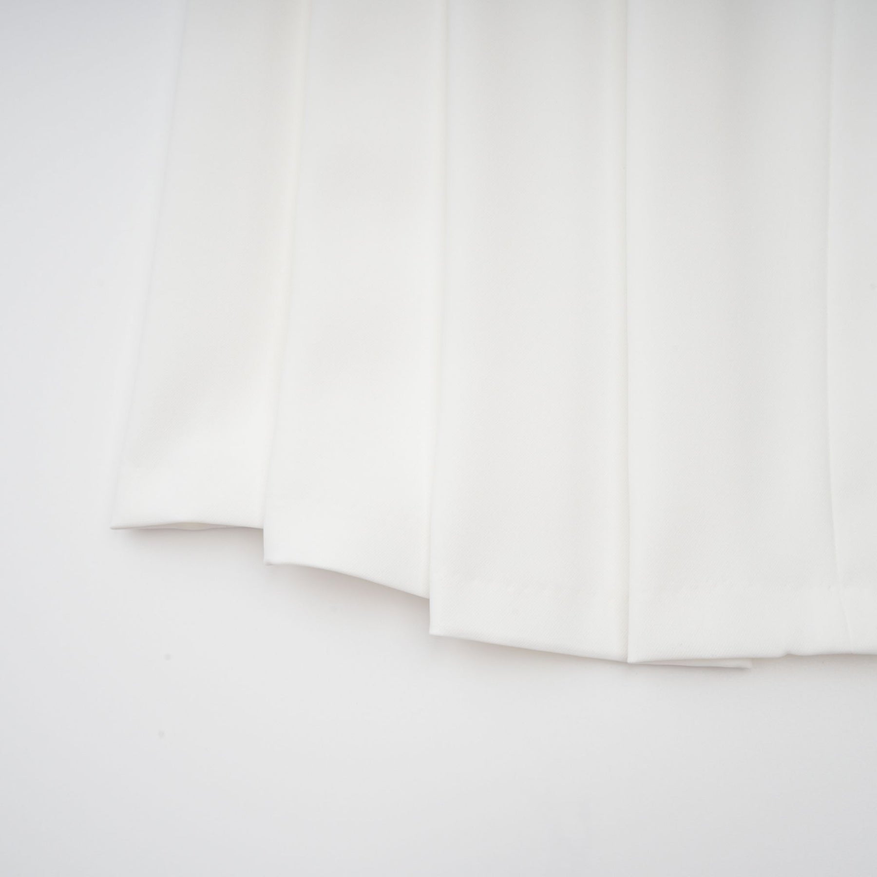 A white matching set featuring a creased top and trousers worn by a model against a plain background