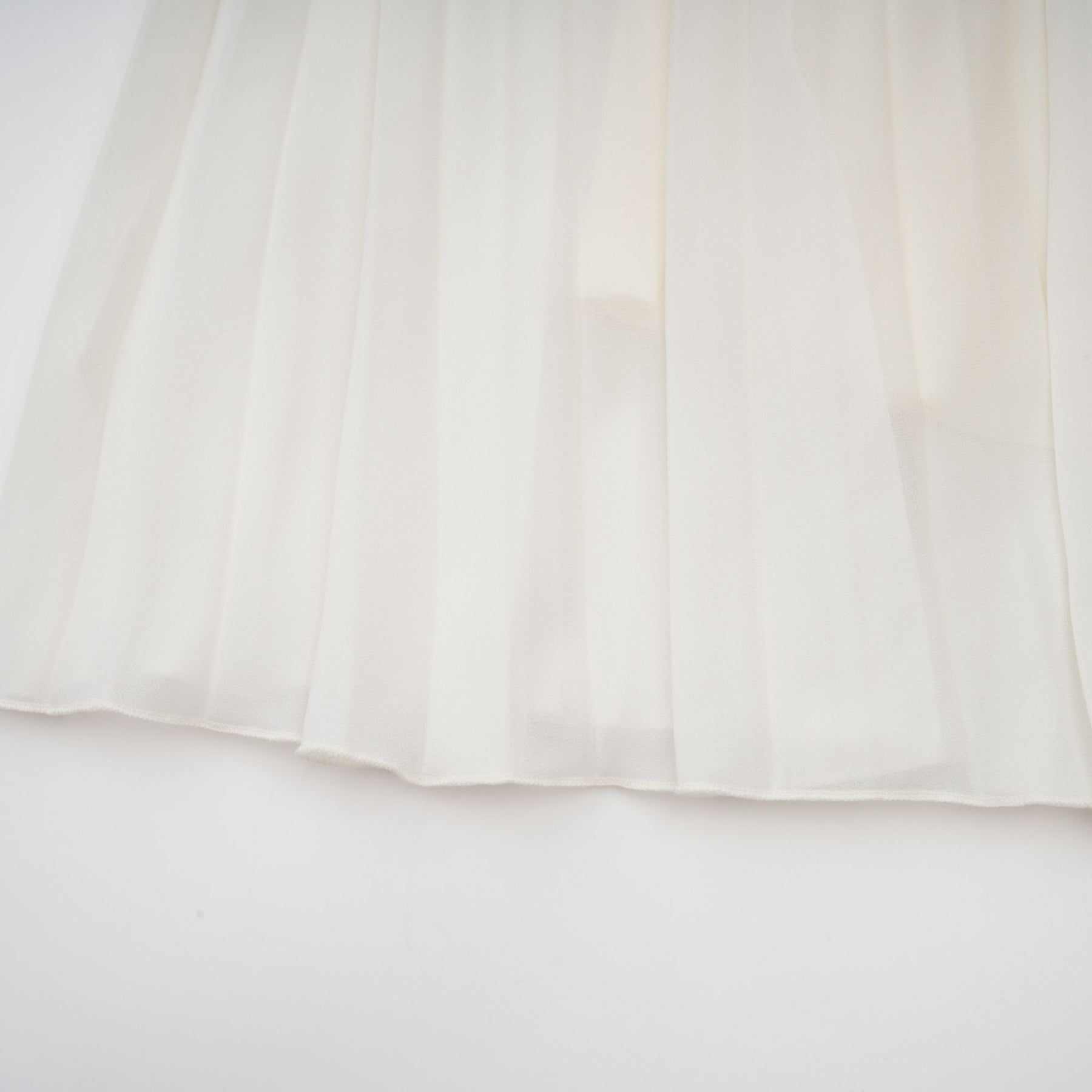 A white matching set featuring a pleated jacket and dress with embellishments The jacket has long sleeves and the dress has a fitted silhouette Both pieces are adorned with delicate embroidery or beadwork creating an elegant ensemble