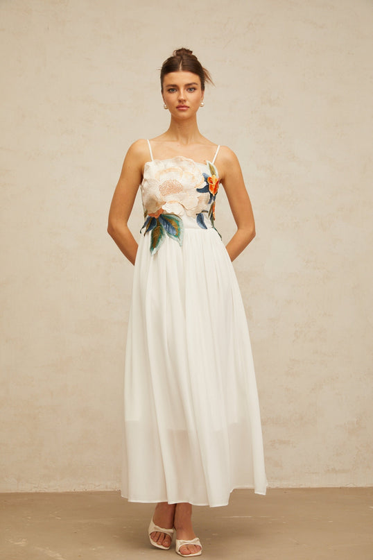 A white maxi dress with floral embroidery and shirred detailing called Josette