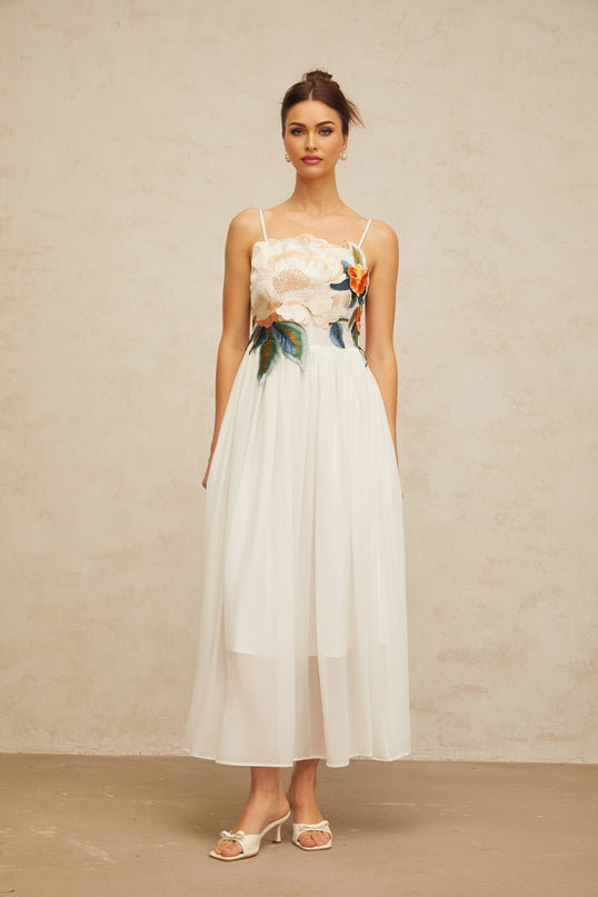 A white maxi dress with floral embroidery and shirred detailing named Josette