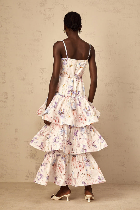A white maxi dress with floral print featuring ruffles and tiered design worn by a woman