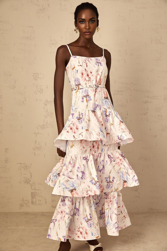 A white maxi dress with floral print featuring ruffles and tiered design worn by a woman