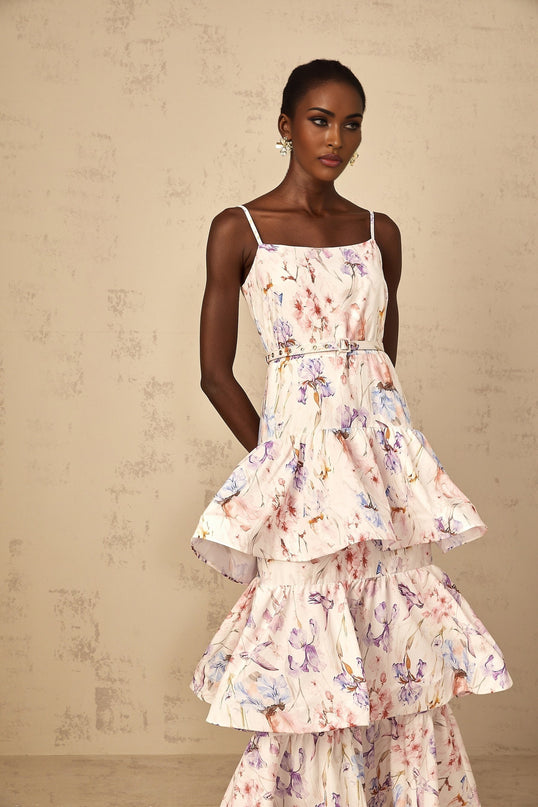 A white maxi dress with floral print featuring ruffles and tiered design worn by a woman
