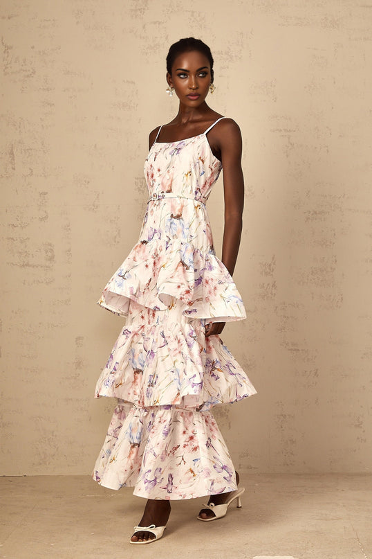 A white maxi dress with floral print featuring ruffles and tiered layers worn by a woman